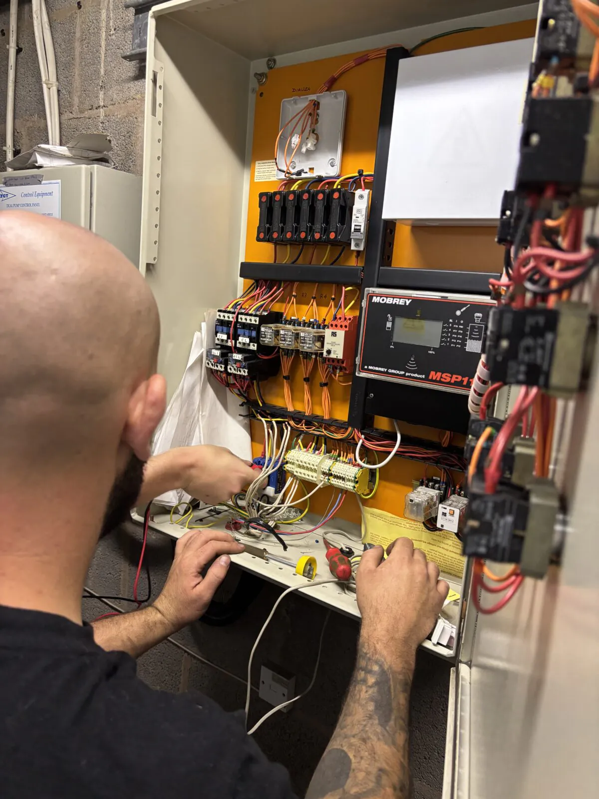 Trebles engineer carrying out maintenance on a control panel on site